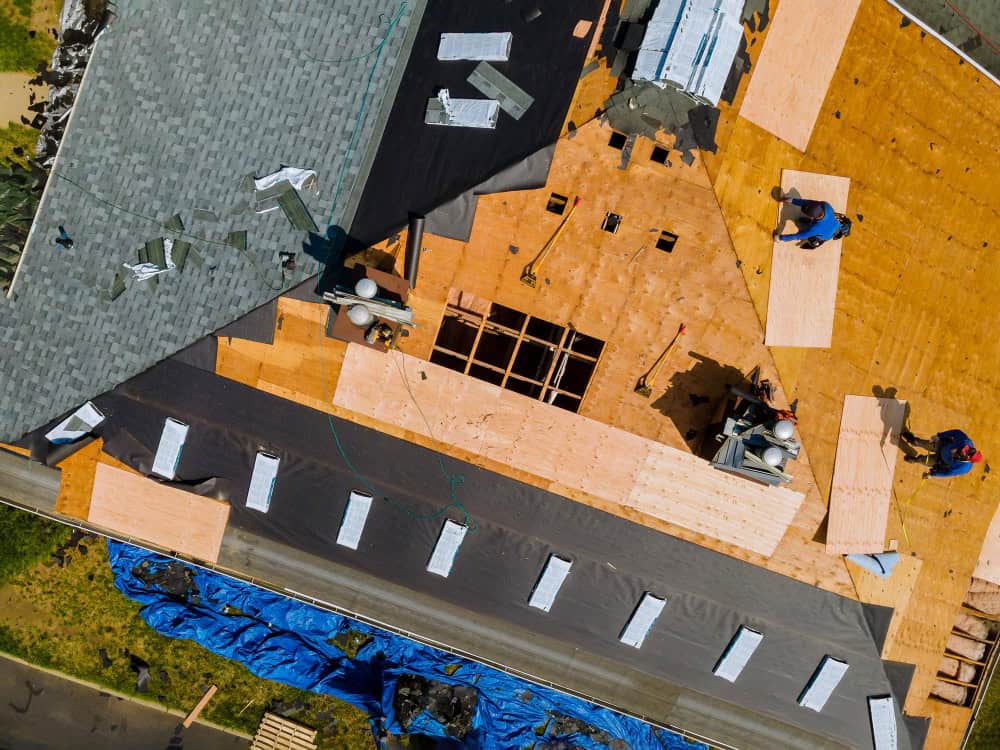 people working on top of the roof replacing roof cover protection