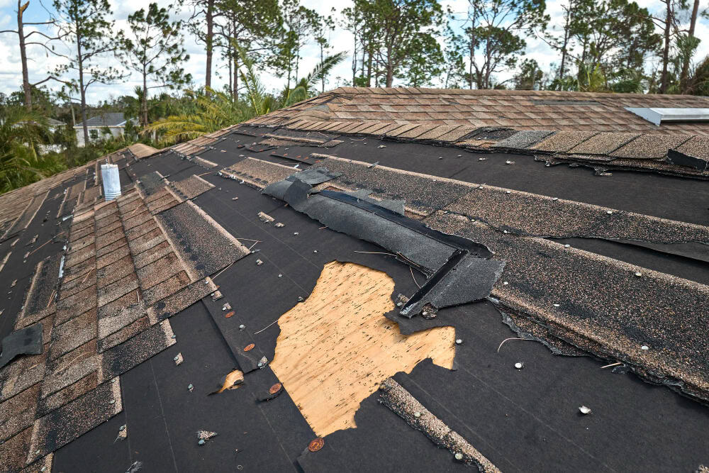 damaged house roof with missing shingles after hurricane in a natural disaster