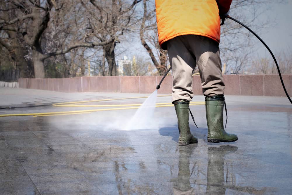 man using pressure washer to wash driveway